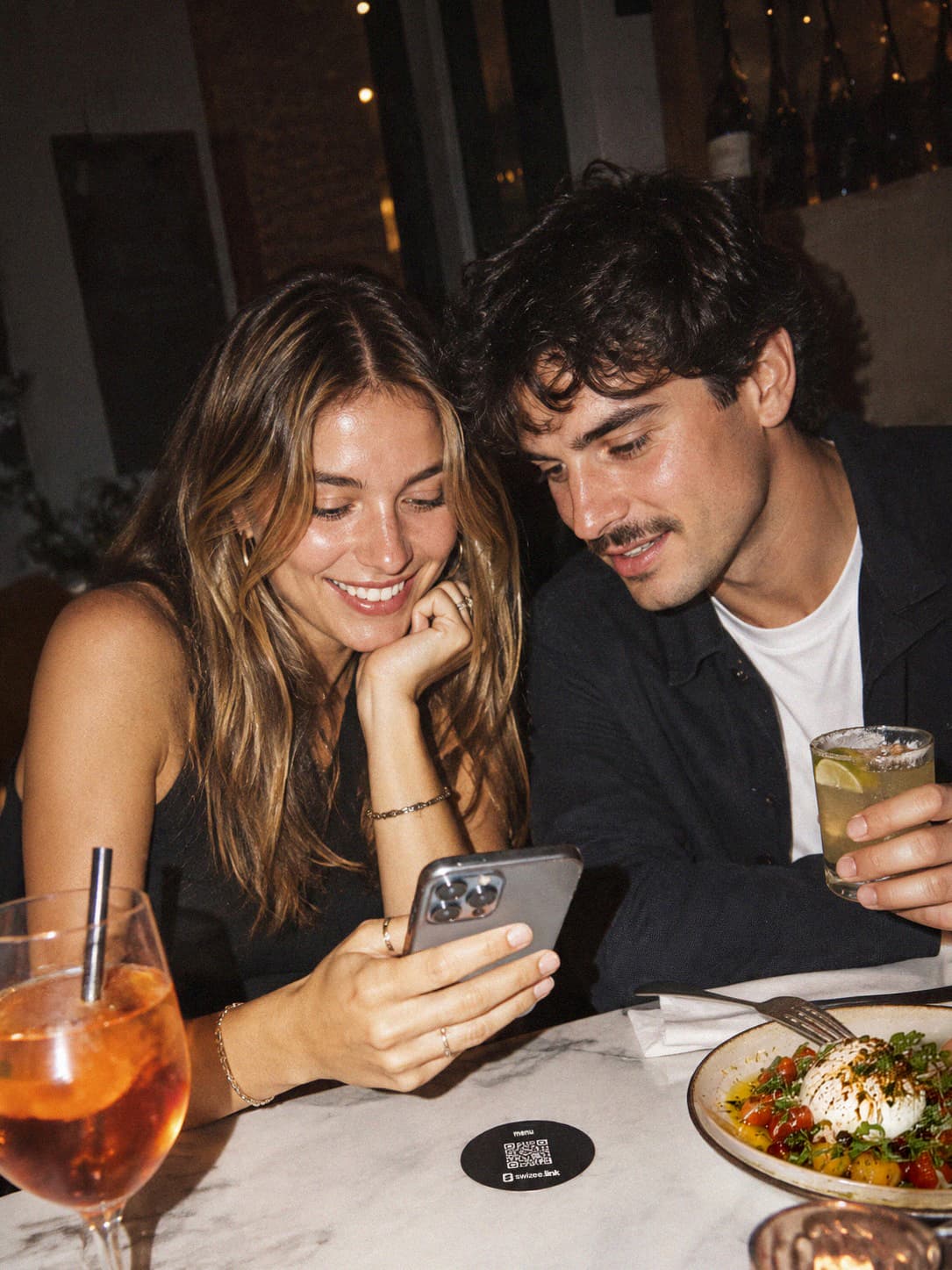 Un couple à table le soir, un sous-verre Swizee posé près des verres